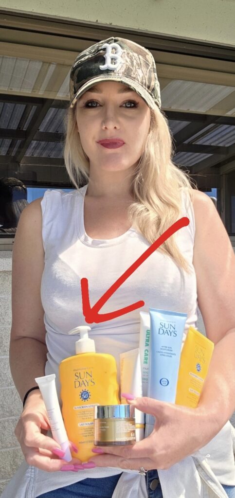 Smiling woman wearing a hat holding a bottle of Sun Days SPF 50+ sunscreen, ready for sun protection